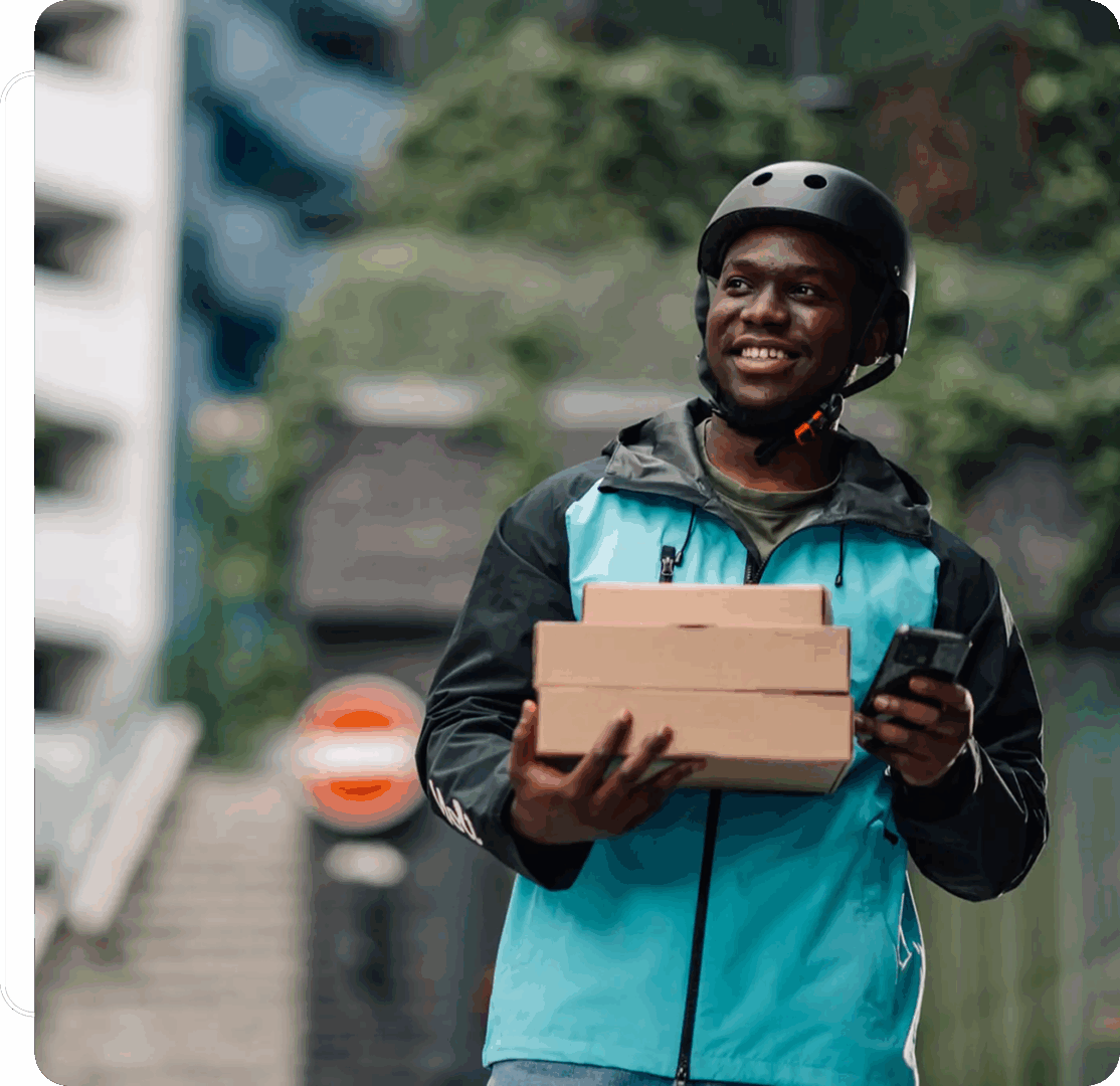 Smiling delivery man holding packages outdoors.
